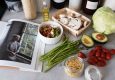 A selection of fresh vegetables and a cookbook in a kitchen setting, promoting healthy cooking. — Elements Smokehouse: Enjoy