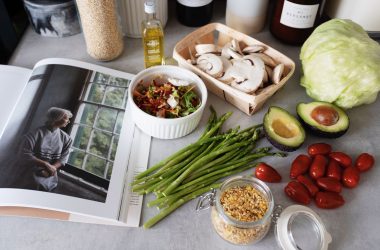 A selection of fresh vegetables and a cookbook in a kitchen setting, promoting healthy cooking. — Elements Smokehouse: Enjoy